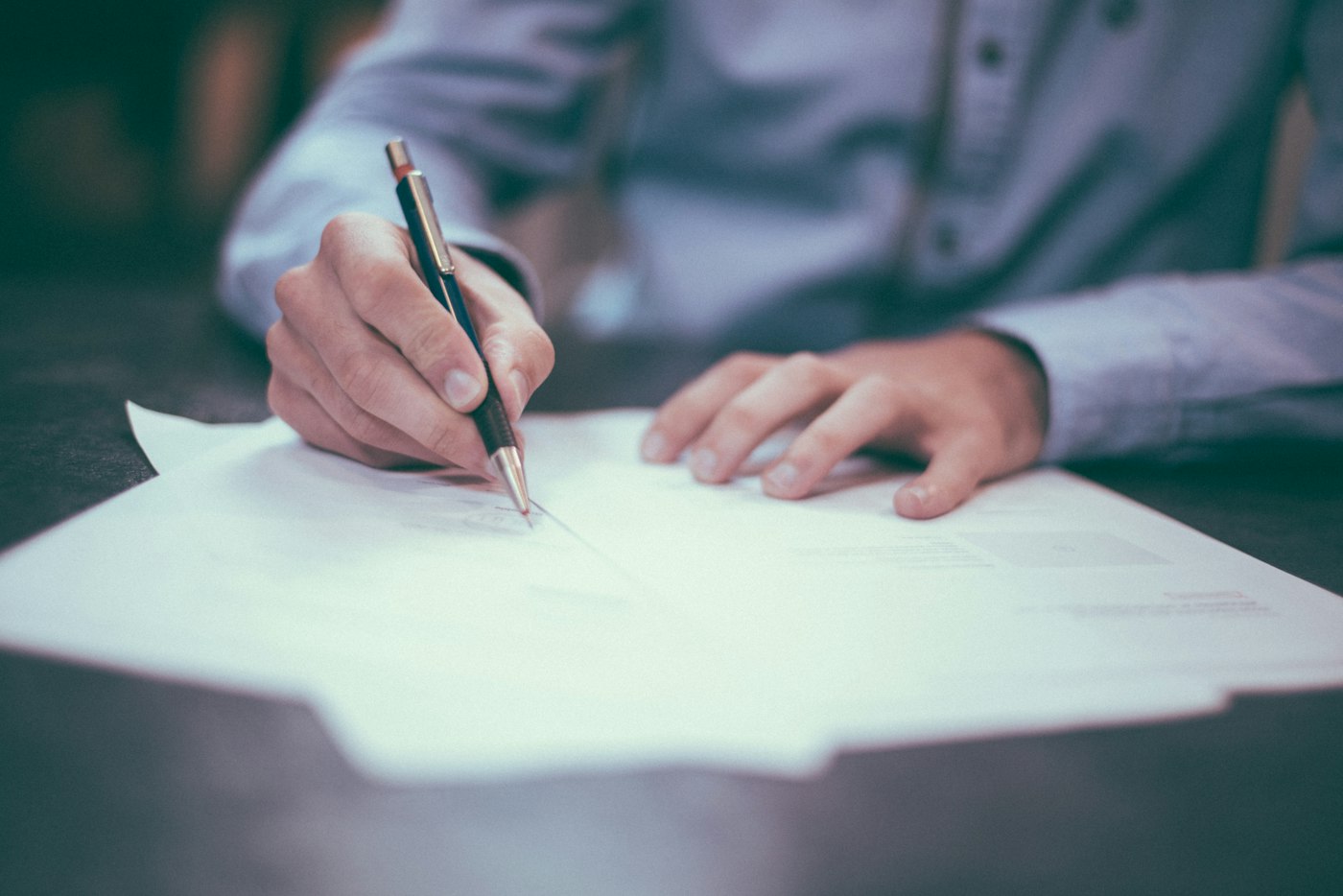 Papers and a pen arranged on a wooden desk